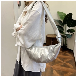 Silver metallic dumpling bag with knotted shoulder strap shown on a model