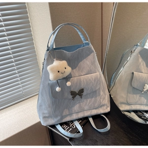 Detail of light blue nylon tote bag with silver butterfly metal ornament and cloud charm