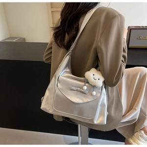 Detail of silver metallic shoulder bag with bow and plush cloud charm on a suit