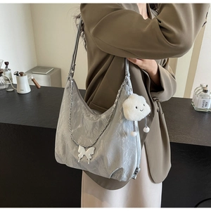 Detail of silver pleated tote bag featuring a metal butterfly chain and cloud plush charm