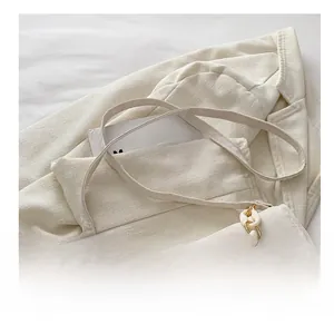Close-up of beige crossbody bag with chunky white chain and gold metal ring detail