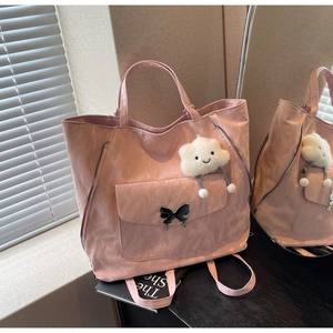 Pink tote bag with pleated texture and black butterfly buckle detail in warm setting