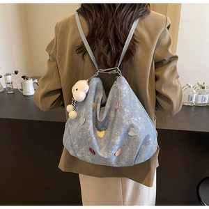 Détail du sac en denim bleu clair avec patchs cœurs colorés et breloque mouton peluche