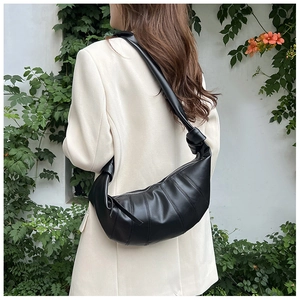 Minimalist black dumpling bag with wide strap and quilted texture shown on a model