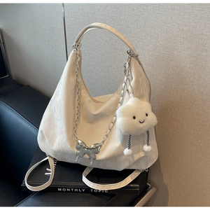 Detailed view of white pleated tote bag with silver butterfly chain and plush cloud charm