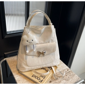 Detail of white textured tote featuring a silver butterfly clasp and cloud charm