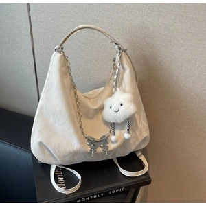 Detail of white nylon tote bag with silver butterfly chain and cloud plush charm