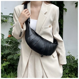 Close-up of black croissant bag with quilted pleats and wide shoulder strap