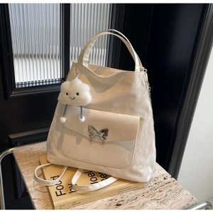 Detail of ivory tote bag with silver butterfly buckle and white fluffy cloud charm