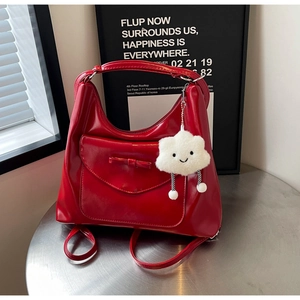 Detail of red patent leather tote bag with bow decoration and cloud plush keychain