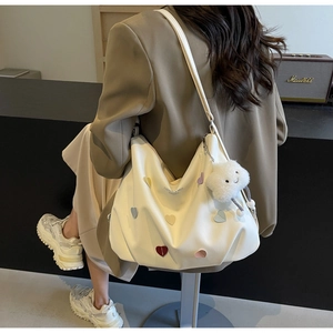 Détail du sac hobo avec patchs de cœur colorés et pendentif nuage en peluche