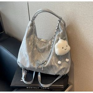 Close-up of silver tote bag with metallic texture, butterfly charm, and plush cloud accessory