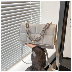 Detail view of silver quilted crossbody bag with purple and gold chunky resin chain strap