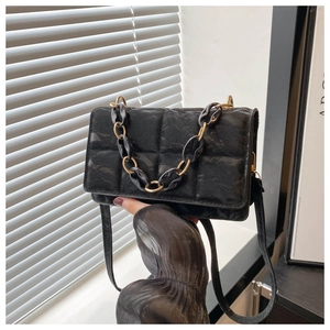 Close-up of black quilted crossbody bag with textured finish and decorative chain detail