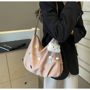 Détail du sac cabas rose avec patchs cœur et breloque nuage porté à l'épaule