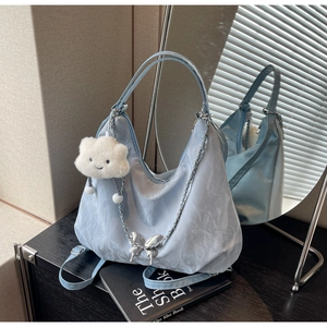 Close-up of light blue pleated tote with metallic butterfly and plush cloud charm