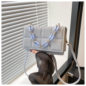 Detail of light blue crossbody bag with square embossed pattern and decorative chunky chain