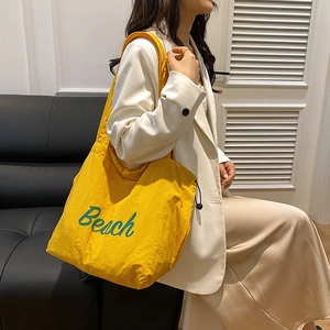 Minimalist bright yellow canvas tote bag with green Beach lettering and drawstring closure