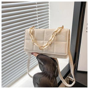Detailed macro view of quilted off-white handbag featuring elegant gold chain handle