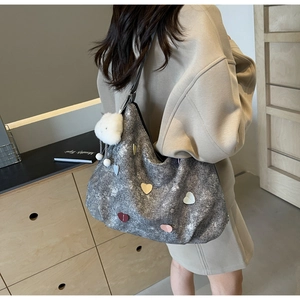 Détail d'un sac bandoulière gris avec écussons cœurs colorés et breloque nuage en peluche