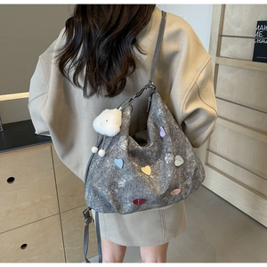 Détail d'un sac hobo gris pailleté avec des patchs en cœur et un charm de nuage