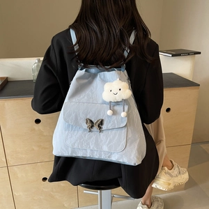 Light blue nylon tote bag with butterfly clasp and white cloud charm shown on model