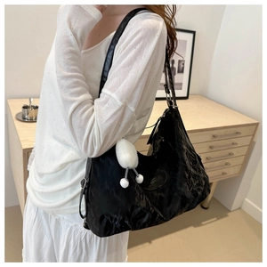 Dettaglio della borsa hobo nera a pieghe con logo e ciondolo a sfera di peluche