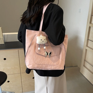 Pink faux leather tote bag with butterfly buckle and cloud charm in a home setting
