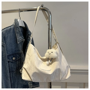 Dettaglio della borsa tote bianco off-white con trama a pieghe e ciondolo a nuvola