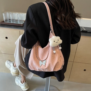 Pink leather tote bag with butterfly chain and cloud charm worn over black blazer