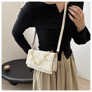 Detail of white quilted crossbody bag featuring a stylish chunky cream chain strap