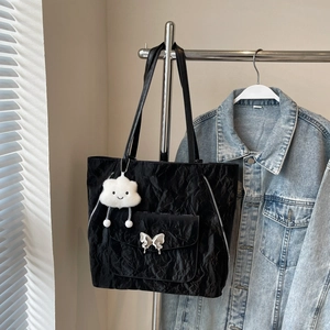 Detail of black pleated tote bag featuring a silver butterfly buckle and cloud charm