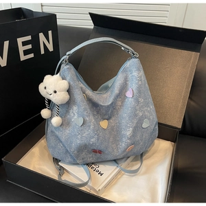 Détails d'un sac cabas en denim bleu clair avec écussons en cœur et breloque nuage