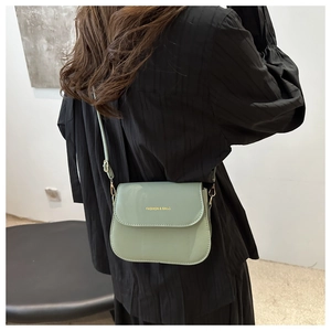 Detail of mint green crossbody bag with gold fashion lettering on smooth leather