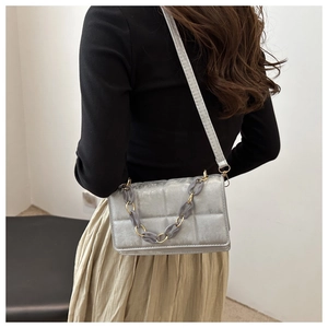 Detailed view of silver-grey quilted crossbody bag with stylish resin link chain strap
