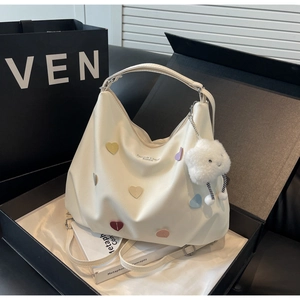 Sac hobo blanc dans une boîte cadeau avec patchs cœurs colorés et breloque nuage