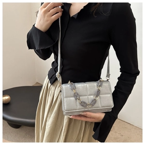 Detail view of silver quilted crossbody bag with stylish resin chain and metallic finish