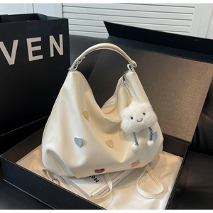 Détail du sac Hobo blanc avec écussons cœurs et breloque nuage sur boîte cadeau