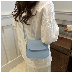 Close-up of a light blue leather crossbody bag with gold Fashion & Bags lettering detail
