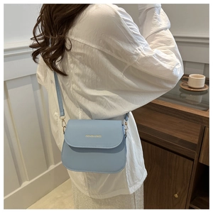 Close-up of light blue leather crossbody bag with golden Fashion & Bags logo detail