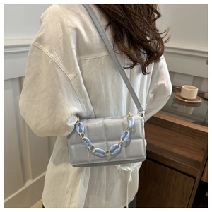 Detail of light blue quilted crossbody bag featuring a thick decorative chain strap