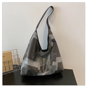 Detailed view of large grey patchwork Hobo bag with textured leather on art book background