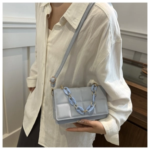 Close-up of light blue quilted crossbody bag with gold and plastic chain detail