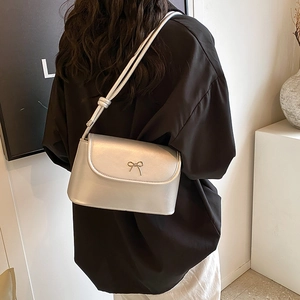 Silver leather crossbody square bag with metallic bow buckle shown on model