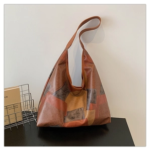Detail view of large tote bag featuring brown and grey PU leather patchwork textures