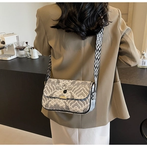 Sac bandoulière chic avec motifs brodés ondulés et large sangle géométrique