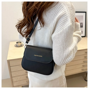 Classic black square crossbody bag with gold fashion text worn by a model in lifestyle setting