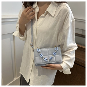 Detail of light blue quilted crossbody bag with acrylic chain and leather strap