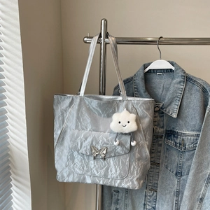 Detail of silver metallic tote bag with butterfly buckle and cloud charm accessory