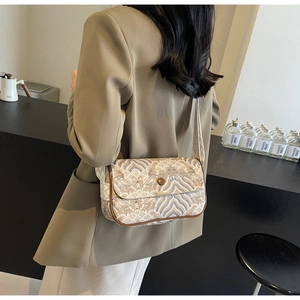 Détail d'un sac à bandoulière aux motifs géométriques avec toile texturée et cuir poli